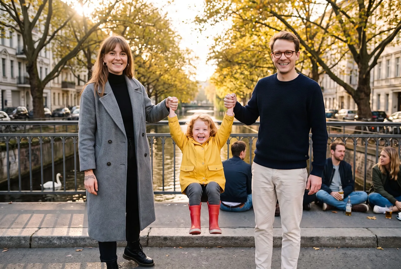 Eine Familie schwingt ihre Tochter an den Händen über die Admiralbrücke am Landwehrkanal in Kreuzberg, Herbstlicht