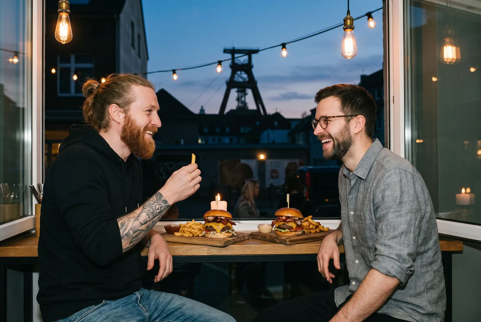 Zwei Freunde mit Burgern am Fenstertisch eines Restaurants im Bochumer Bermuda3Eck in der Abenddämmerung