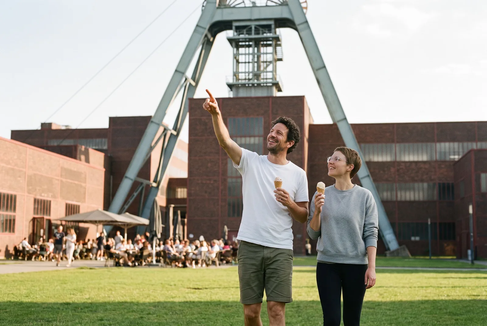 Ein Paar mit Eis vor dem Förderturm der Zeche Zollverein in Essen an einem Sommernachmittag